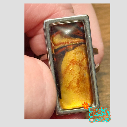 Hand-painted golden amber and dark brown swirl glass cabochon ring on a stainless steel open-back band by Cindy Clampitt Creations