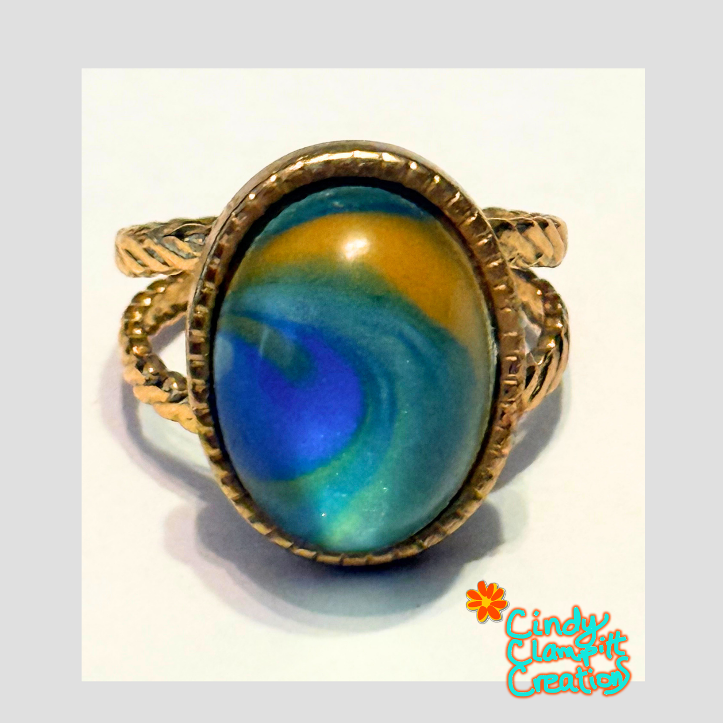 Hand-painted teal, cobalt blue and golden amber swirl oval glass cabochon ring on an 18K gold plated twisted rope open cuff band by Cindy Clampitt Creations